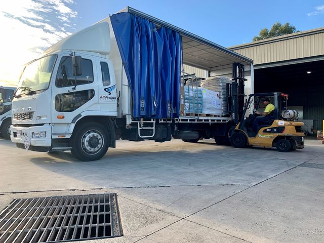 A forklift loading a pallet into the side of an All Freight Carrying curtainsider at the Yandina depot