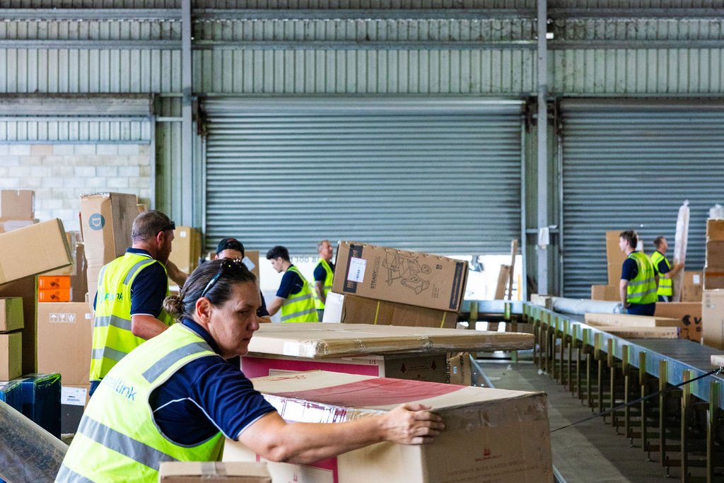 Depot team sorting freight along the belt at Yandina