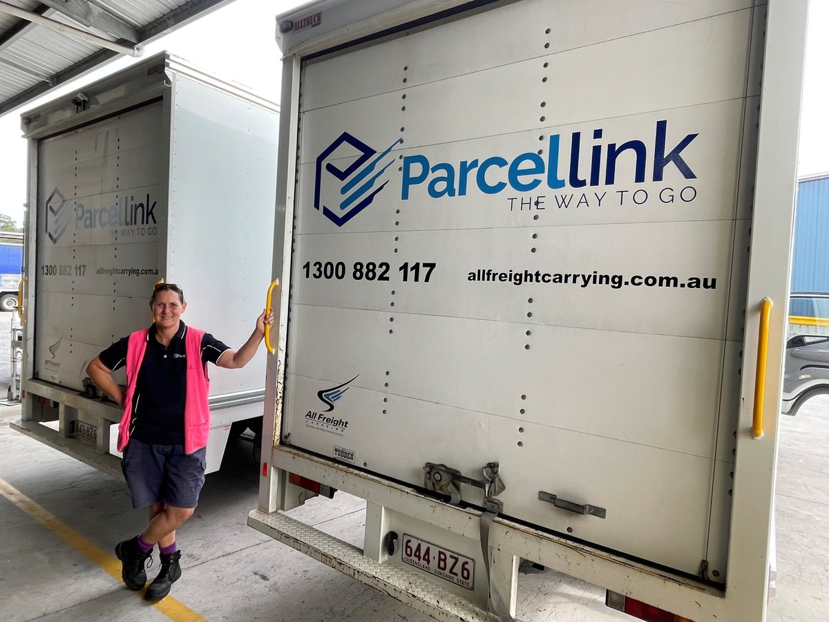 A Parcel Link driver at the rear doors of two Parcel Link delivery trucks at the Yandina depot